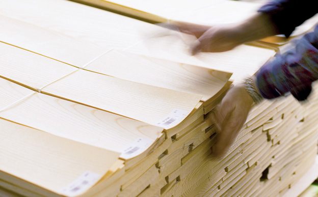 Close-up of hands sorting spliced veneer faces at the flexible customer-oriented facility in Durham.